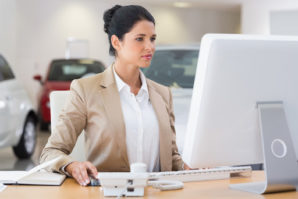 An auto dealership accounting leader, like this woman at her computer, employs bookkeeping practices that are essential to her dealership’s financial success.