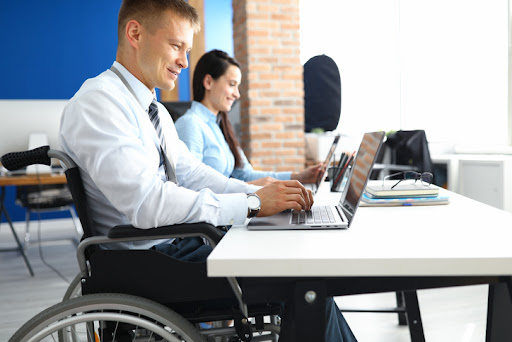 The Work Opportunity Tax Credit (WOTC) can provide significant tax savings to employers who recruit new employees from the credit’s qualified groups. Disabled veteran and a female colleague at a desk working on laptops.