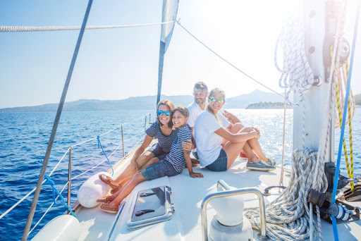 Wealthy family of four on the bow of a sailboat relaxing because they have a tax planning and compliance partner.