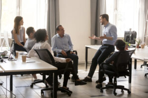 An auto dealership sales team discussing accounting practices in a bright office space.