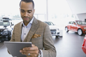 auto dealer year end review - Man using digital tablet in car dealership showroom