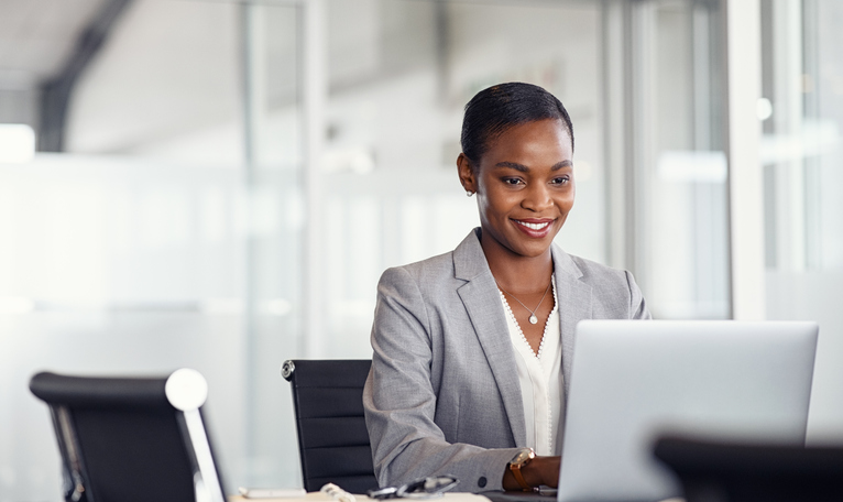 A woman wearing a blazer works at her laptop in a brightly lit office. The SECURE ACT 2.0 and Form 5500 revisions introduced significant changes to employee benefit plans that will go into effect for the 2023 filing year.