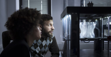 Two People Looking at a 3D Printer.web